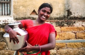 Woman from South Asia smiling, holding pot with clean water